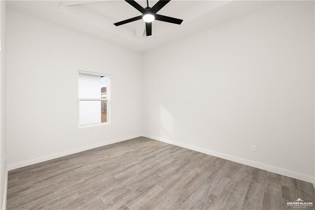 Spare room with wood finished floors, ceiling fan, and a tray ceiling | Image 9