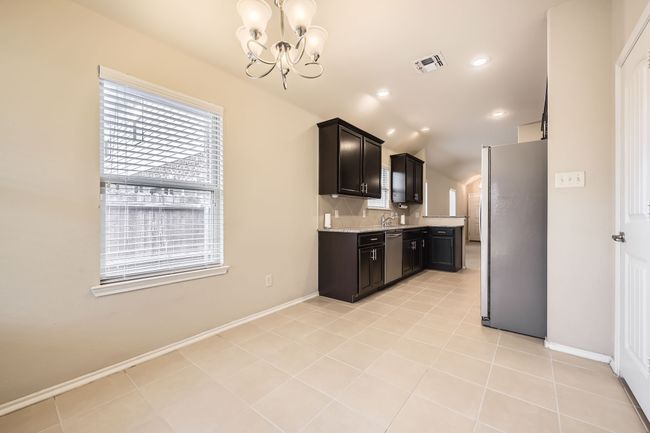 Kitchen featuring stainless steel appliances, a chandelier, decorative backsplash, light tile patterned floors, and recessed lighting | Image 7