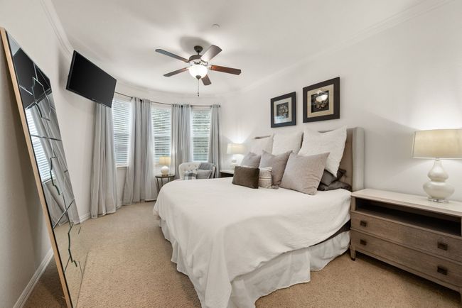 Upstairs Bedroom featuring tall ceilings, ornamental molding, light colored carpet, walk in closet and a ceiling fan | Image 26