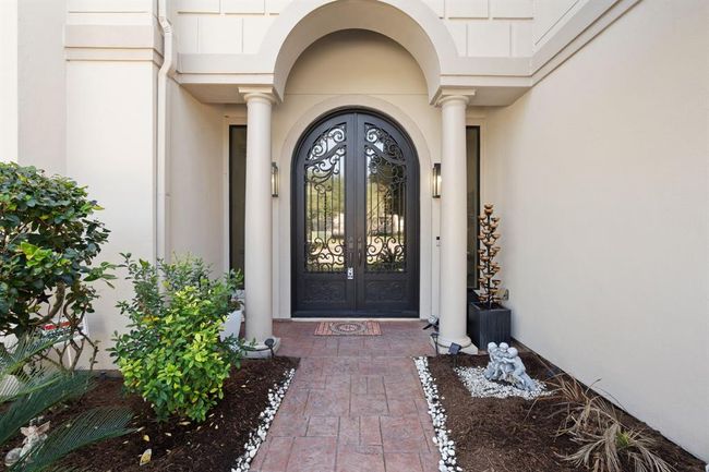 Inviting exterior with an elegant arched front door, framed by decorative columns. Fresh landscaping enhances curb appeal and creates a welcoming atmosphere. | Image 5