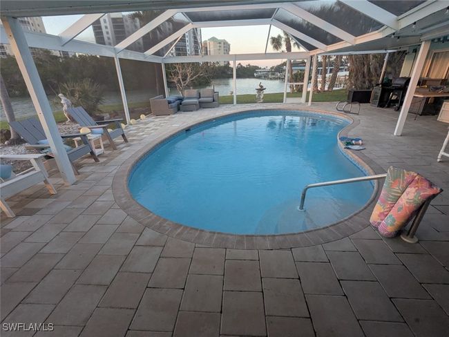 Pool at dusk with screen enclosure, a water view, an outdoor pool, and a patio | Image 30
