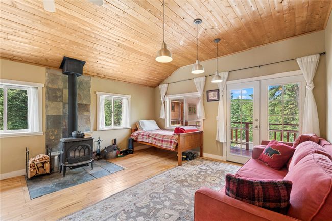 Apartment featuring access to outside, a wood stove, multiple windows, hardwood / wood-style floors, and vaulted ceiling | Image 51