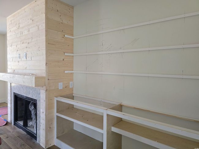 Unfurnished living room with wood finished floors, a premium fireplace, and wooden walls | Image 4