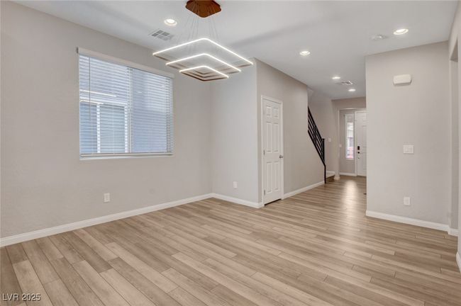 Empty room featuring light wood-style floors, a chandelier, baseboards, recessed lighting, and stairway | Image 7