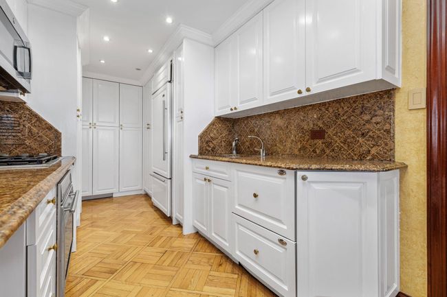 Kitchen featuring white cabinetry, appliances with stainless steel finishes, decorative backsplash, recessed lighting, and dark stone countertops | Image 10