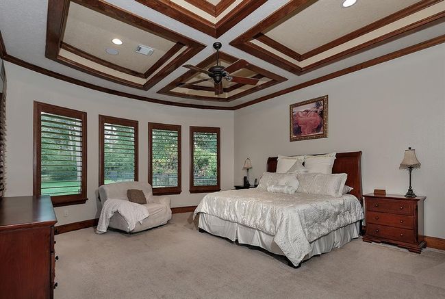 Generous main level primary retreat features elegant, coffered ceilings with wood trim accents and many large windows offering amazing views | Image 18