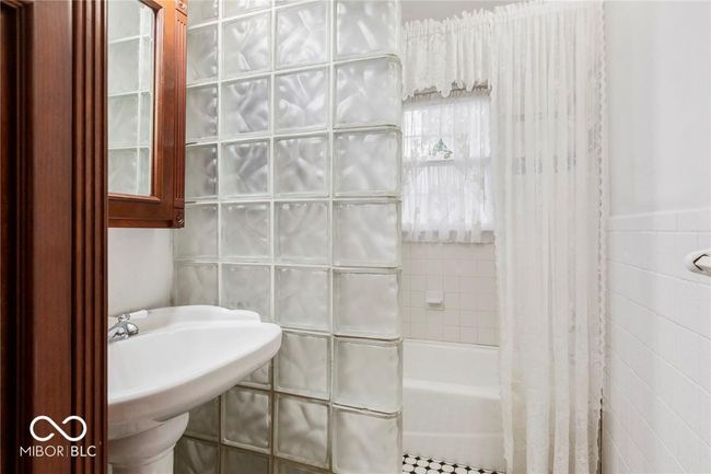 bathroom featuring tile walls and shower / tub combo with curtain | Image 32