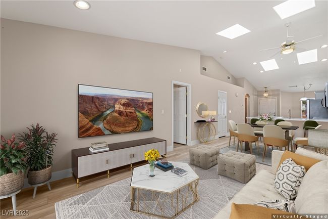 Living room with wood finished floors, a ceiling fan, recessed lighting, a skylight, and high vaulted ceiling | Image 5