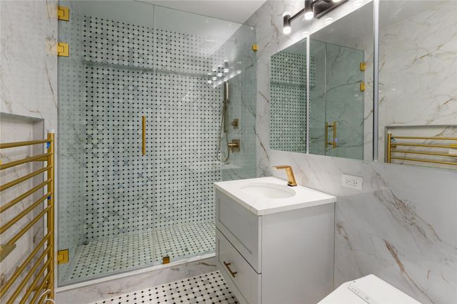Full bathroom featuring a marble finish shower, vanity, and tile walls | Image 16