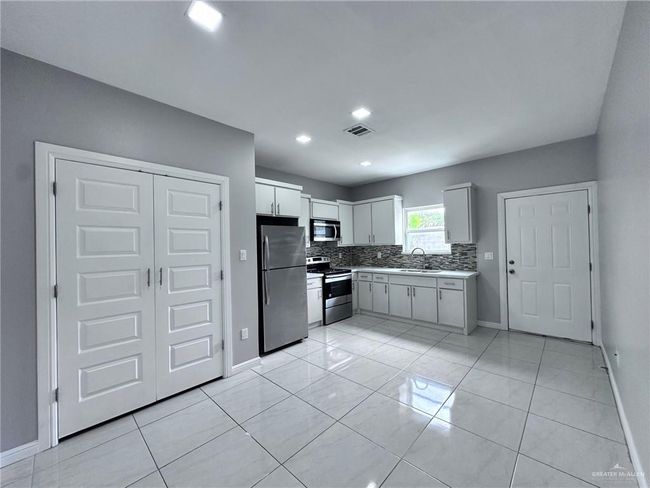 Kitchen featuring light countertops, stainless steel appliances, baseboards, decorative backsplash, and a sink | Image 6