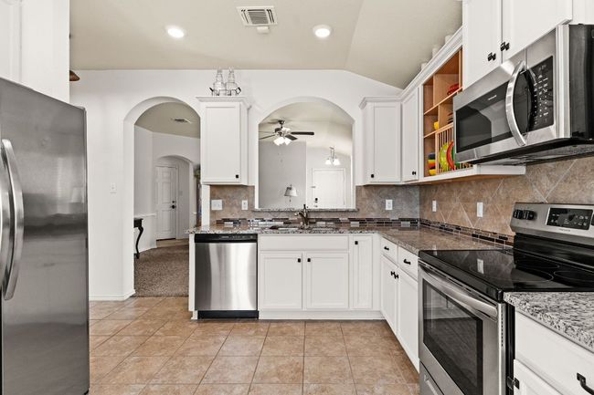 Kitchen featuring visible vents, arched walkways, a sink, appliances with stainless steel finishes, and a ceiling fan | Image 9