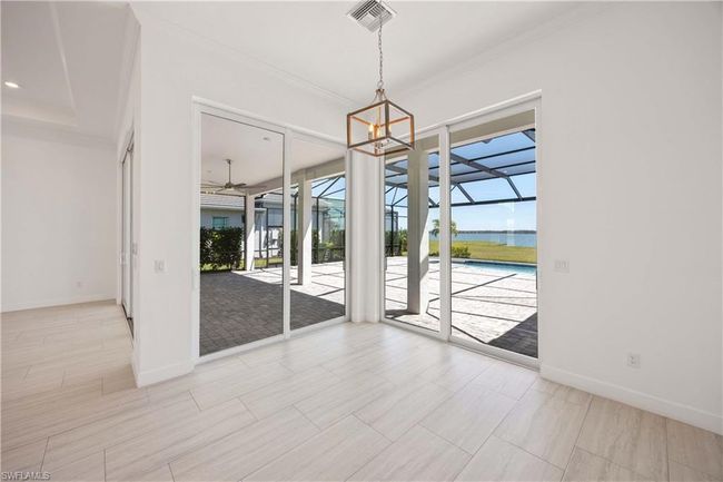 Empty room featuring a sunroom, visible vents, baseboards, ornamental molding, and ceiling fan with notable chandelier | Image 13
