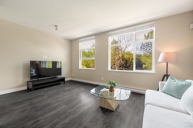Living area featuring dark wood-style flooring, a baseboard heating unit, and baseboards | Image 4