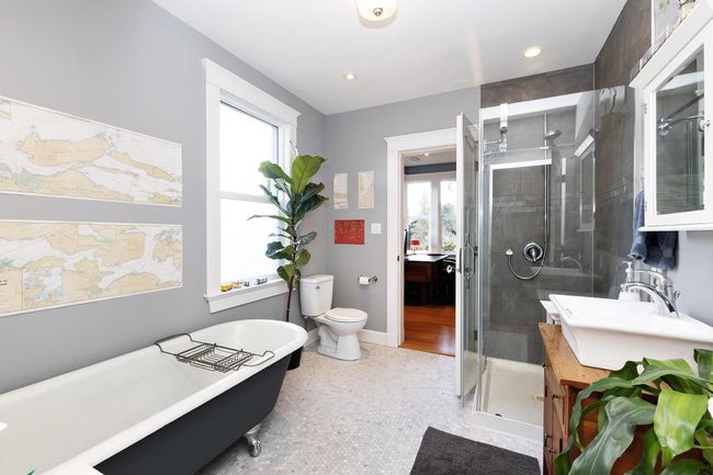 Bathroom featuring toilet, a stall shower, baseboards, a soaking tub, and vanity | Image 23