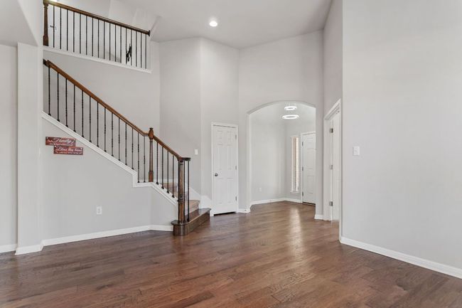 Entryway featuring baseboards, a towering ceiling, wood finished floors, stairway, and arched walkways | Image 7