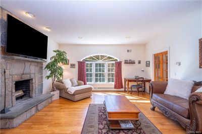 Warm and inviting, this spacious family room features a beautiful stone fireplace and flows seamlessly from the kitchen, creating the perfect space for both relaxation and entertaining. | Image 3