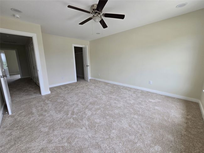 Unfurnished bedroom with carpet, baseboards, a ceiling fan, and a spacious closet | Image 21