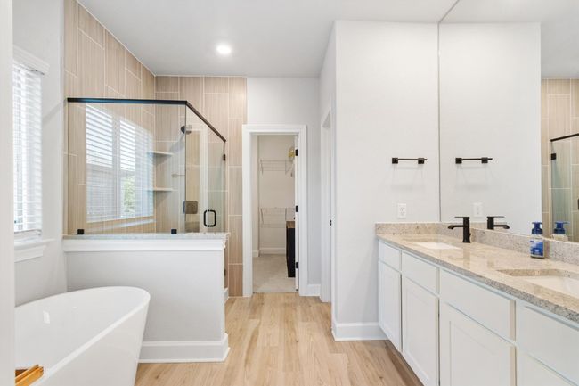 Full bathroom featuring a stall shower, wood finished floors, a walk in closet, a freestanding tub, and double vanity | Image 14