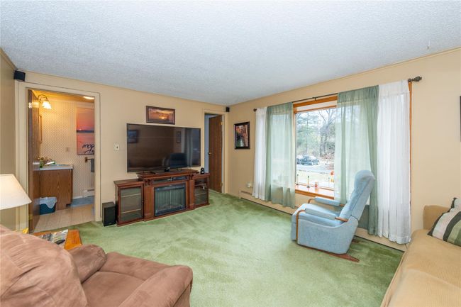 Living area with a textured ceiling, carpet, and a glass covered fireplace | Image 12
