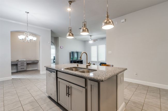 Kitchen with a center island with sink, ceiling fan with notable chandelier, a sink, stainless steel dishwasher, and light tile patterned floors | Image 13