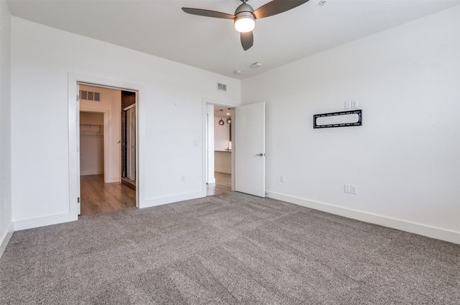 Unfurnished bedroom featuring carpet, a spacious closet, and a ceiling fan | Image 17