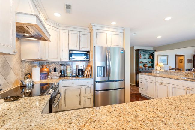 Kitchen featuring appliances with stainless steel finishes, custom exhaust hood, backsplash, recessed lighting, and light stone counters | Image 50