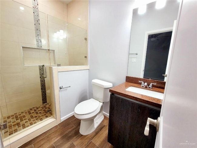 Bathroom with a shower stall, vanity, toilet, wood finished floors, and baseboards | Image 11