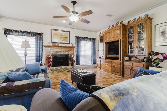Living room featuring ornamental molding, plenty of natural light, a brick fireplace, and hardwood / wood-style floors | Image 17