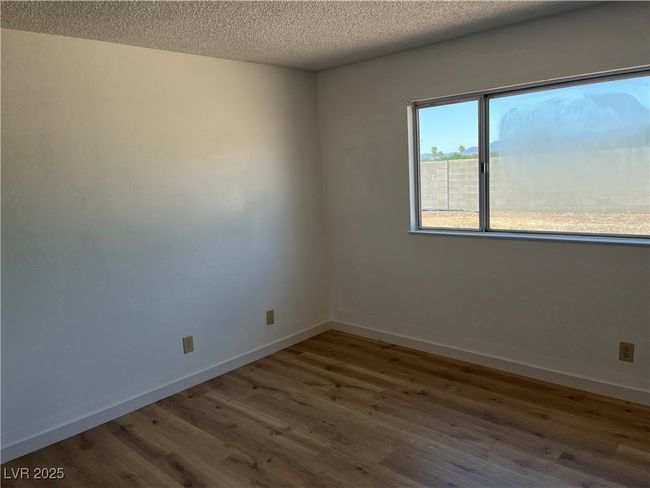 Unfurnished room featuring wood finished floors, a textured ceiling, and baseboards | Image 22