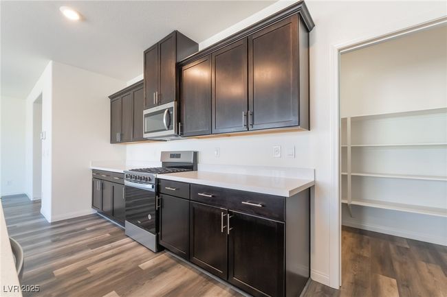 Kitchen featuring appliances with stainless steel finishes, wood finished floors, light countertops, and dark brown cabinets | Image 12