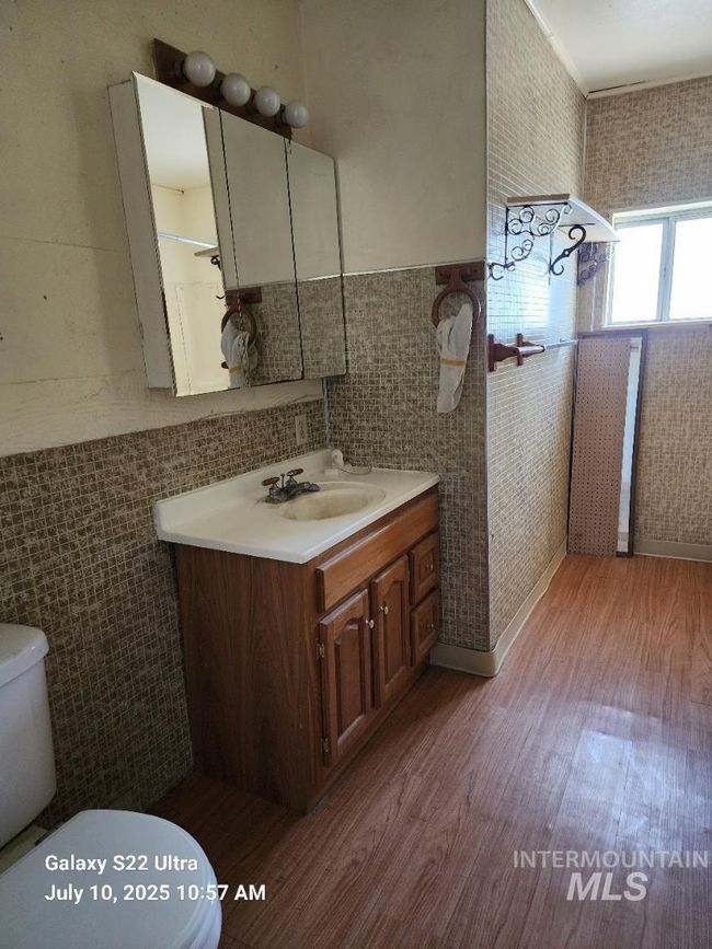 Bathroom featuring wood finished floors, tile walls, vanity, and wainscoting | Image 22
