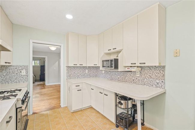 Kitchen featuring white cabinetry, white range with gas stovetop, light hardwood / wood-style flooring, and backsplash | Image 5