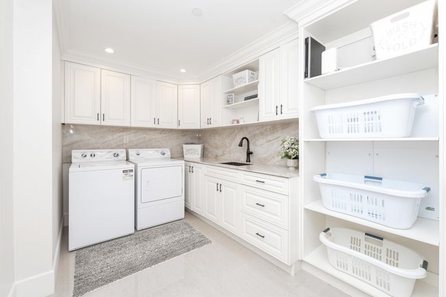 Clothes washing area featuring light tile patterned flooring, recessed lighting, washing machine and clothes dryer, a sink, and cabinet space | Image 17
