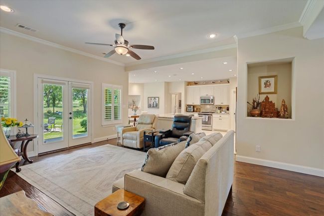 Living room with ornamental molding, dark wood-type flooring, healthy amount of natural light, baseboards, and a ceiling fan | Image 7