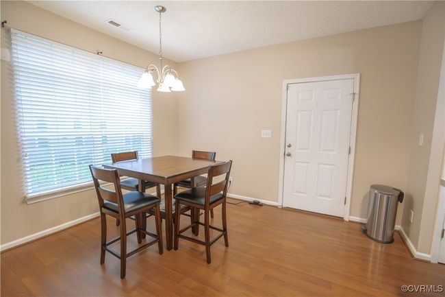 Dining room featuring an inviting chandelier, light wood finished floors, visible vents, and baseboards | Image 7