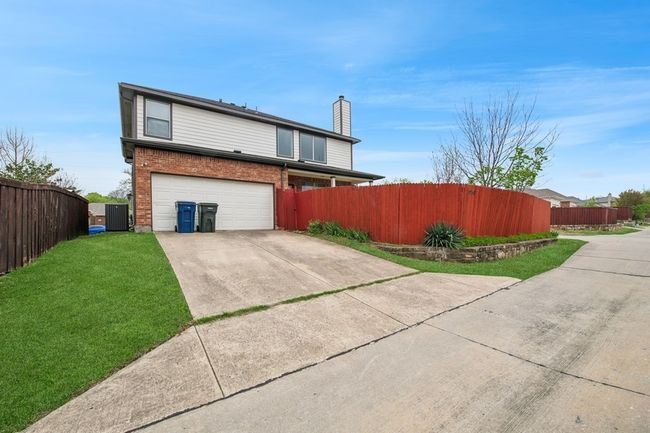 View of home's exterior featuring a lawn, fence, brick siding, an attached garage, and concrete driveway | Image 4