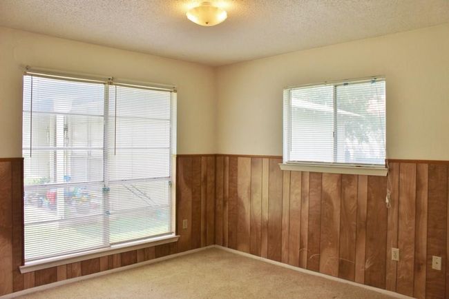 Carpeted empty room featuring plenty of natural light, wood walls, and a textured ceiling | Image 4