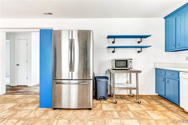 Kitchen with stainless steel appliances, blue cabinetry, light countertops, and stone finish floors | Image 24