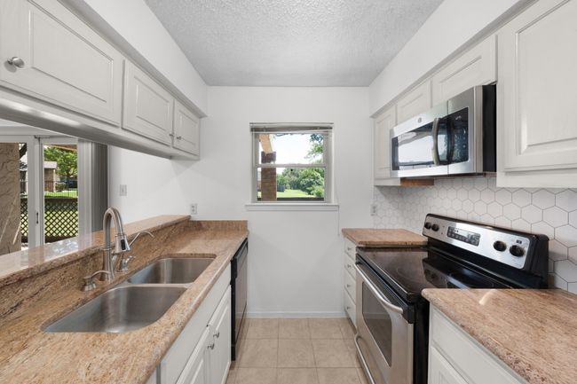 Updated galley kitchen with double sinks, tile floors and backsplash, and nice appliances. Refrigerator is negotiable. | Image 11