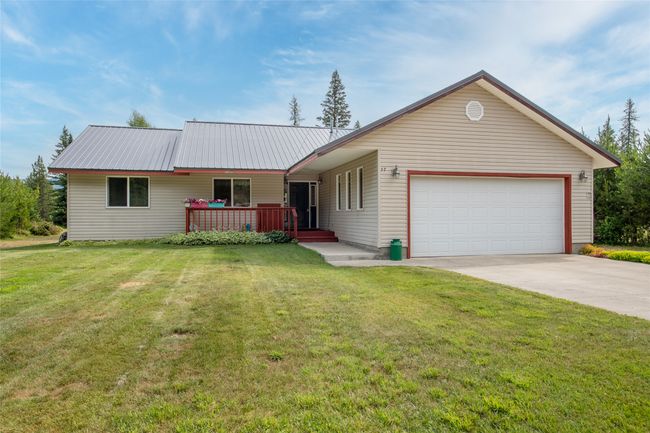 Single story home featuring a garage, concrete driveway, a metal roof, and a front yard | Image 5