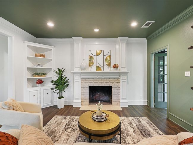 Living room with crown molding, visible vents, a fireplace, and dark wood-style flooring | Image 5