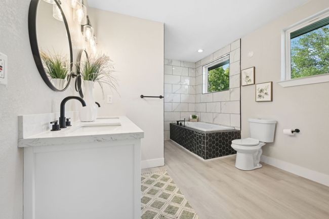 Full bath with a relaxing tiled tub, toilet, baseboards, wood finished floors, and double vanity | Image 21