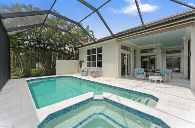 View of swimming pool with a patio, ceiling fan, a pool with connected hot tub, and glass enclosure | Image 16