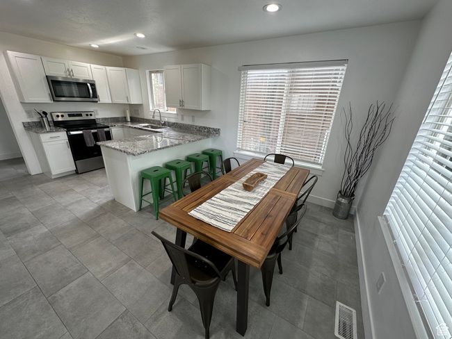 Kitchen with stainless steel appliances, a sink, recessed lighting, a peninsula, and white cabinetry | Image 17