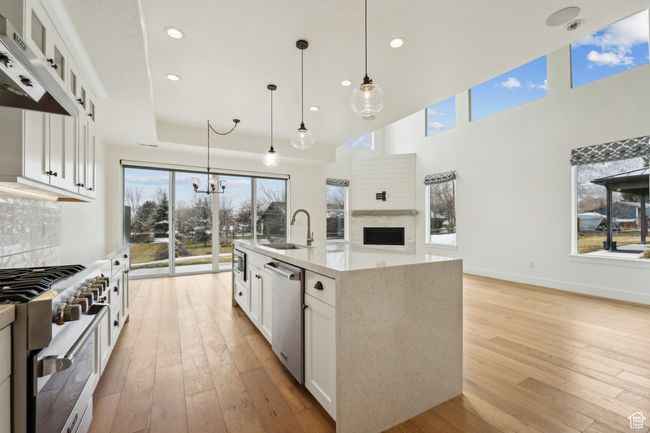 Kitchen featuring under cabinet range hood, a sink, backsplash, light wood-style floors, and appliances with stainless steel finishes | Image 13