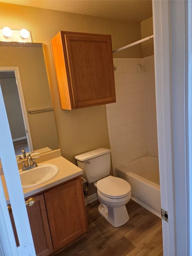 Bathroom with vanity, wood finished floors, shower / tub combination, and a textured wall | Image 23