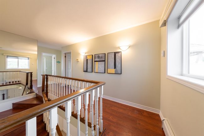 Corridor featuring baseboards, dark wood-style flooring, an upstairs landing, and a baseboard heating unit | Image 8
