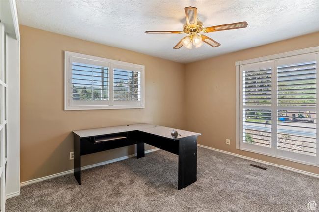 Unfurnished office featuring ceiling fan, carpet flooring, a textured ceiling, and baseboards | Image 22
