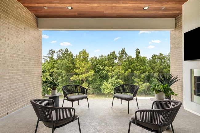 Tucked just off the third-floor media lounge, this covered terrace offers a tranquil, tree-lined backdrop with the added comfort of a fireplace, ideal for unwinding or watching the game outdoors. | Image 28