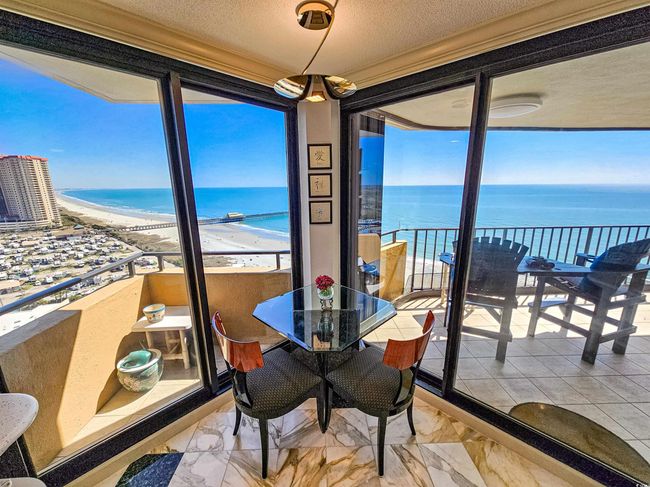 Dining space featuring a view of the beach, a textured ceiling, marble finish floor, and a water view | Image 13